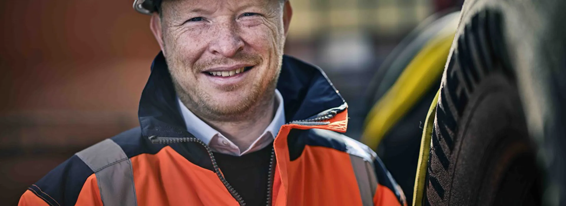 Person in safety gear smiling near tires.