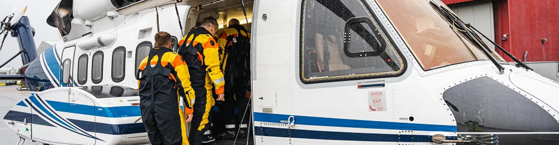 People in safety gear boarding a helicopter.