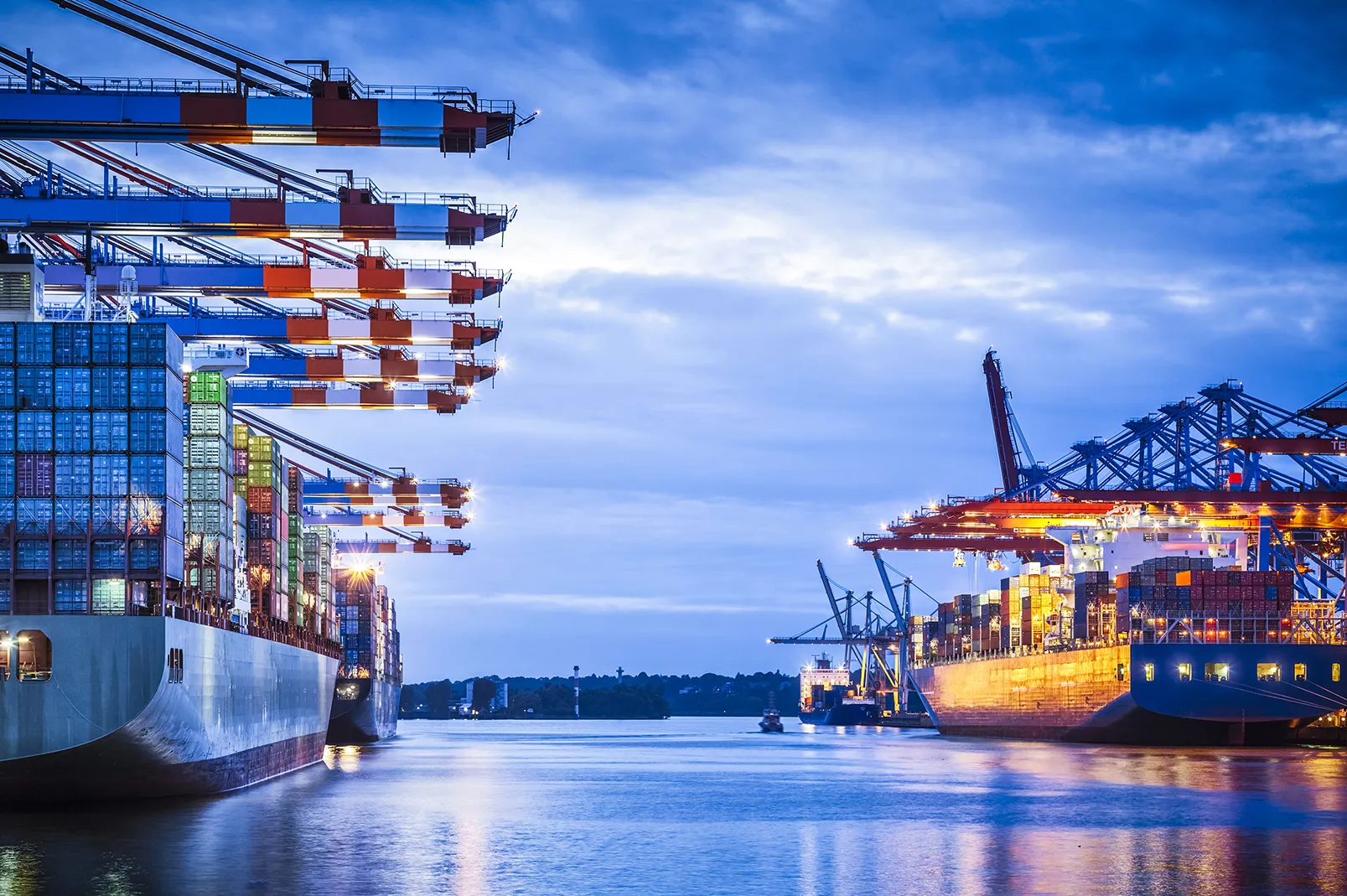 Vibrant port scene at dusk with moored container ships, cranes, and stacked containers.