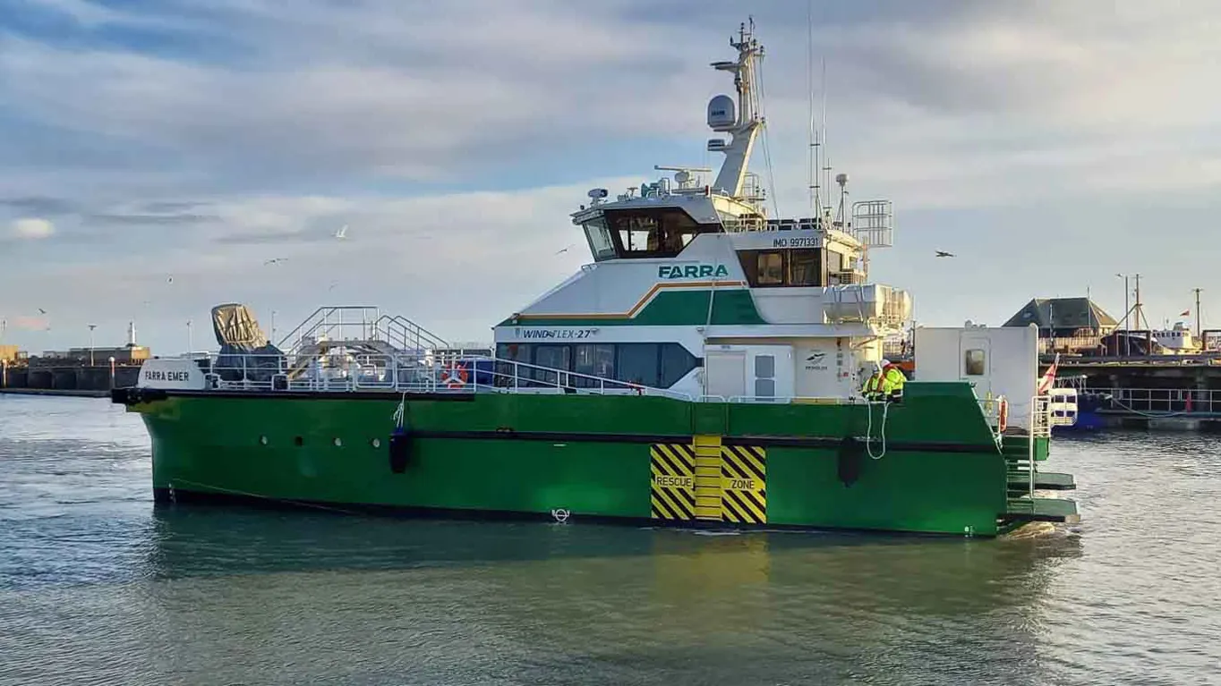 Green and white vessel on water with crew visible.