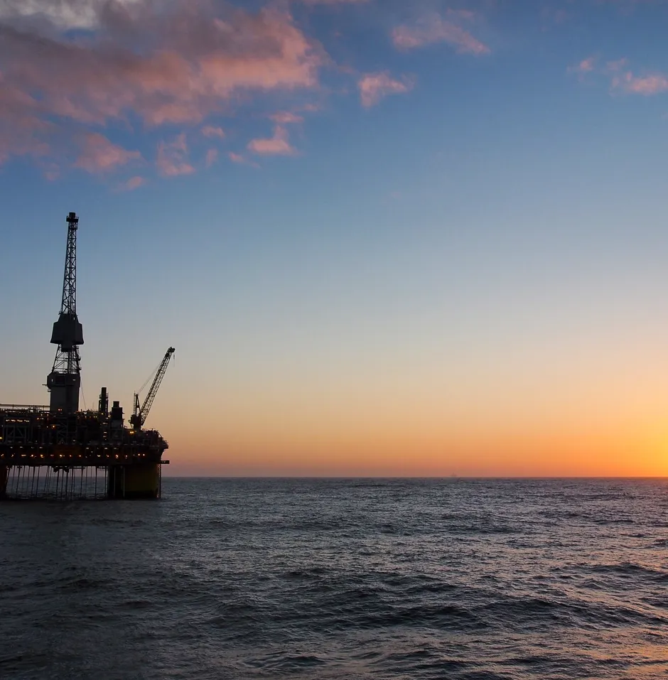 Oil rig silhouetted against a sunset.
