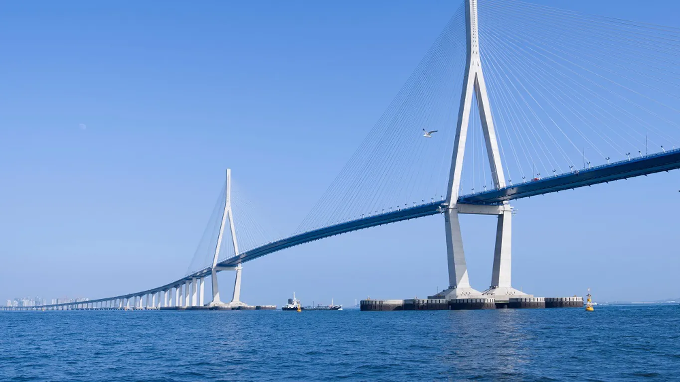 Suspension bridge over blue water and clear sky.
